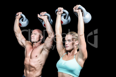 Fit man and woman lifting kettlebells