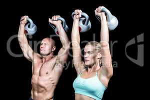 Fit man and woman lifting kettlebells