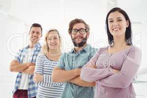 Portrait of smiling business people standing in row with arms cr