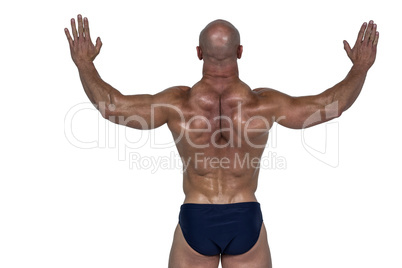 Rear view of muscular man with arms raised