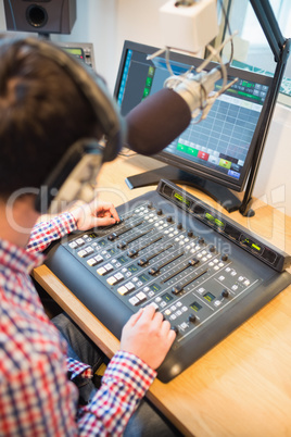 Radio host using sound mixer on table