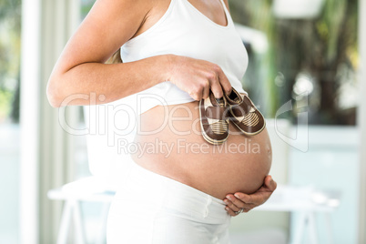 Midsection of woman with baby shoes