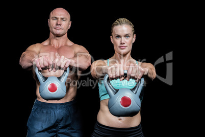 Portrait of muscular man and woman lifting kettlebells