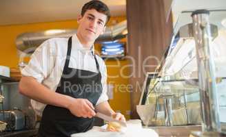 Male worker cutting sandwich on counter