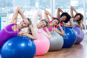 Smiling women stretching on exercise balls with hands behind hea