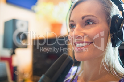 Young radio host wearing headphones using microphone studio