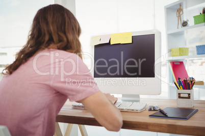 Rear view of hipster working on computer