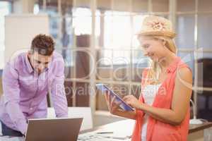 Business woman using digital tablet with male colleague working