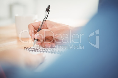 Man writing on spiral table at desk