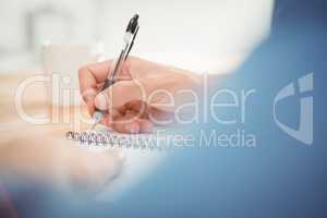 Man writing on spiral table at desk