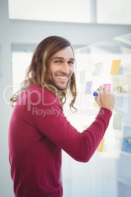 Portrait of happy hipster writing on sticky note