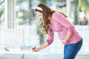 Businesswoman writing note on paper