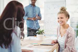 Smiling woman discussing with coworker