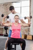 Fit woman lifting dumbbells with trainer