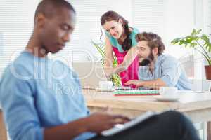 Woman pointing at laptop while discussing with man at desk