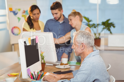 Businessman using on computer with colleagues in background