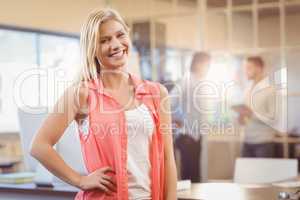 Businesswoman with hand on hip standing against male colleagues