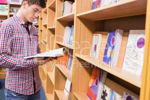 Young man reading book in library