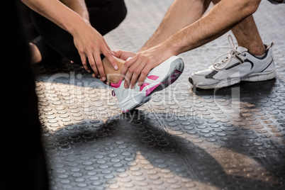 Man holding leg of an injured woman at the gym