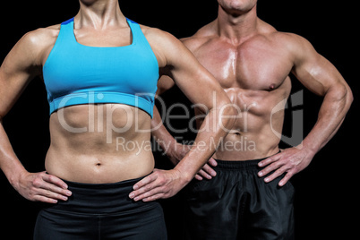 Midsection of muscular woman and man standing with hands on hip