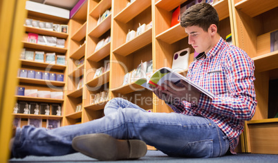 Low angle view of young man reading book  in library