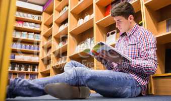 Low angle view of young man reading book  in library