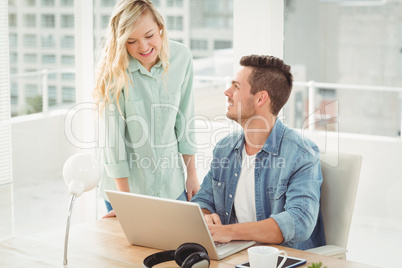 Smiling young coworkers working on laptop