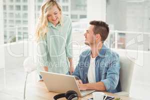 Smiling young coworkers working on laptop