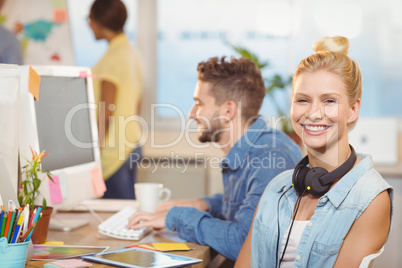 Smiling businesswoman sitting against employees