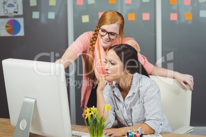 Smiling female employee discussing with colleague in office