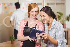 Smiling businesswomen using digital tablet in office