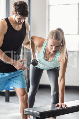 Sporty woman using dumbbells with personal trainor