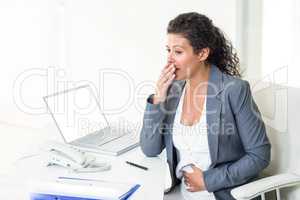 Pregnant businesswoman looking away while yawning