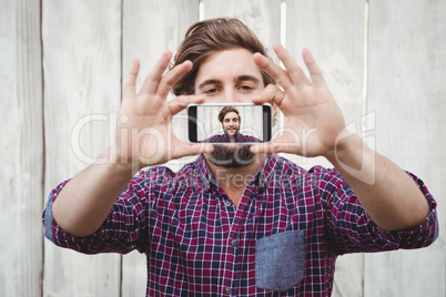 Hipster taking self portrait on smartphone