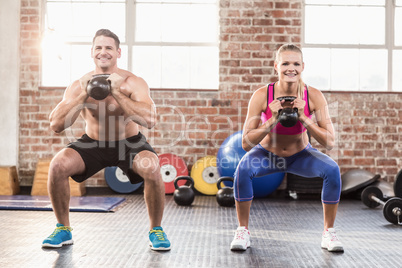 muscular smiling couple with kettlebells