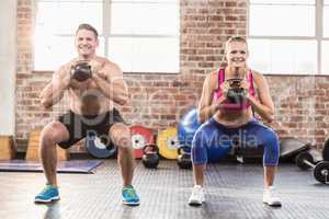 muscular smiling couple with kettlebells