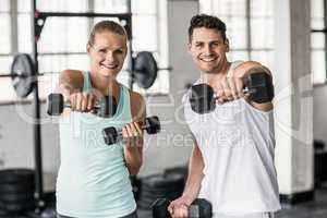 couple exercising with dumbbells in gym