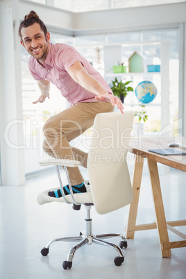 Happy businessman standing on swivel chair