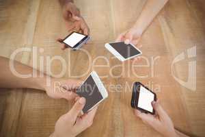 Close-up of cropped hands using mobile phones at desk