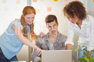 Businesswomen discussing with male colleague with laptop