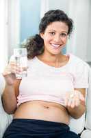 Happy pregnant woman taking pill at home
