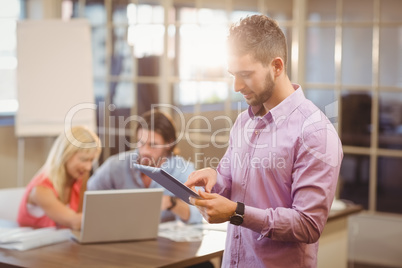Businessman using digital tablet with colleagues on laptop