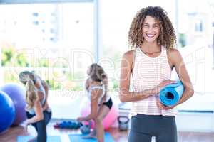 Portrait of woman holding exercise mat and smiling