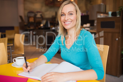 Happy young woman writing on book