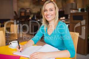 Happy young woman writing on book