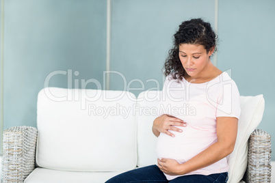 Sad woman sitting on sofa against wall