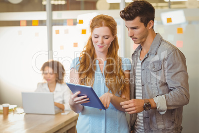 Businesswoman showing digital PC to businessman