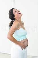 Pregnant woman looking up while touching her belly