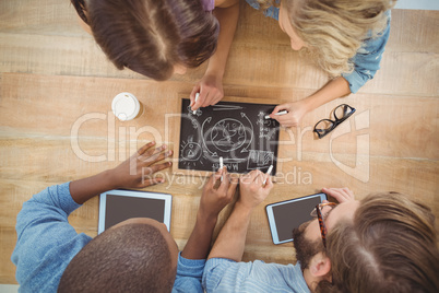 Overhead view of people writing business terms on slate