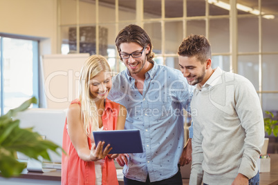 Businesswoman showing something to male colleagues on digital ta